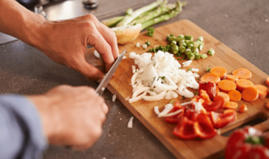 Man cutting vegetables on a wooden cutting board